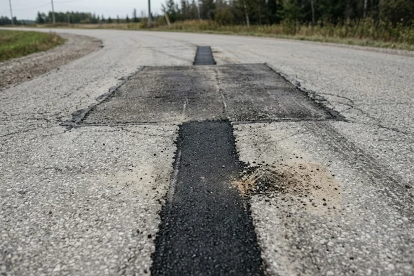 Narrow restored asphalt strip after slot trench backfill